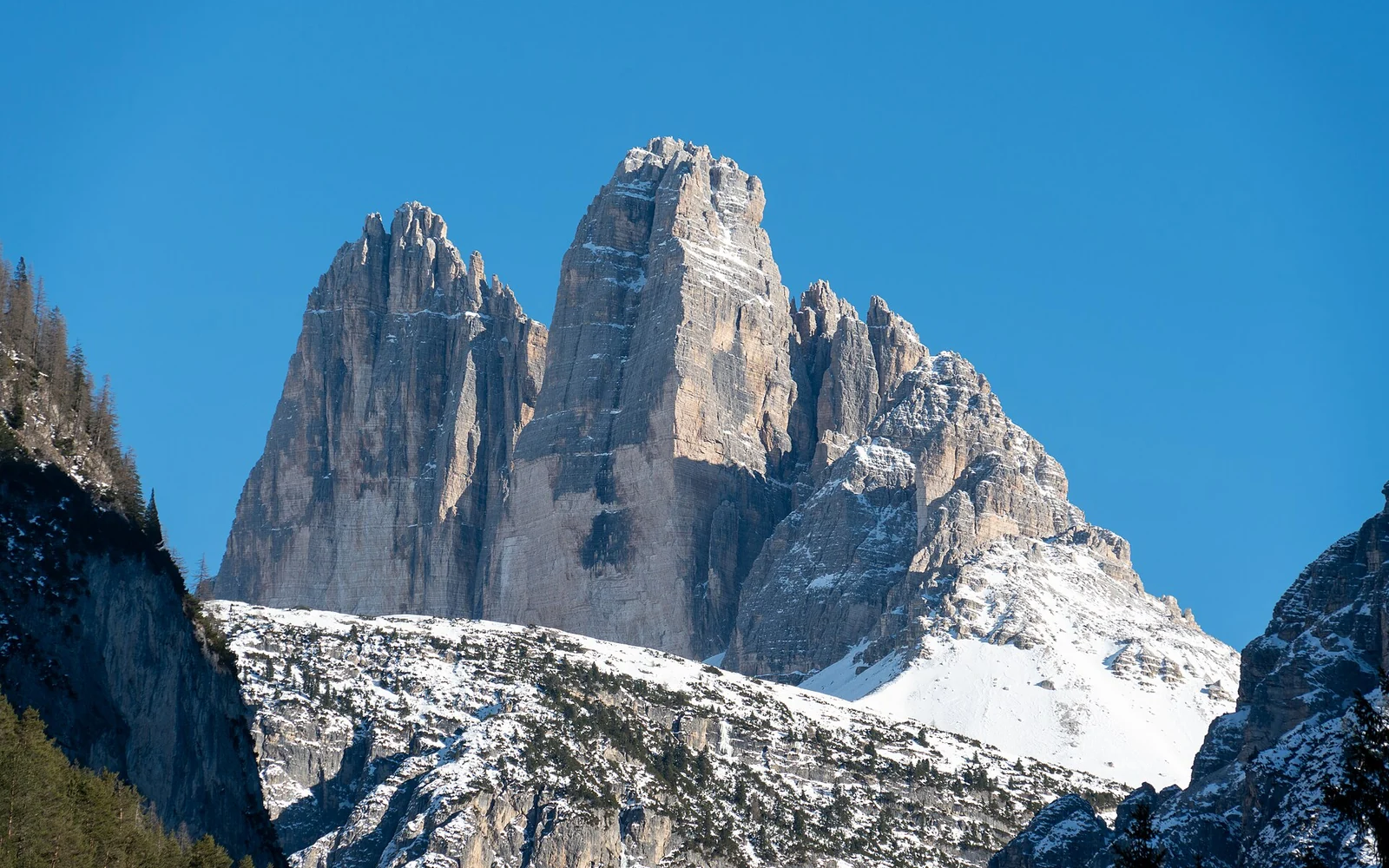 The three peaks of Tre Cime di Lavaredo rise above snow-covered slopes in the Sexten Dolomites.